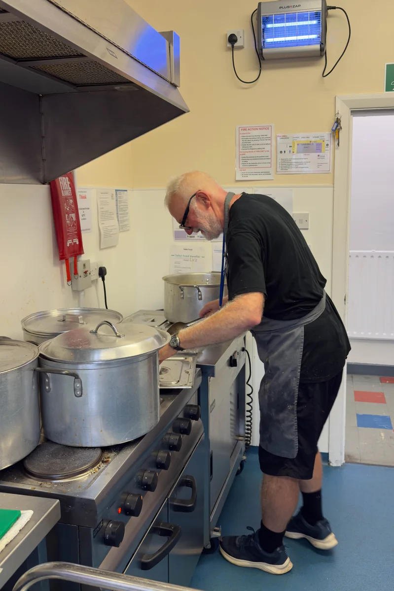 Trinity Mission volunteer cooking hot meals with large stock pots on the commercial stove